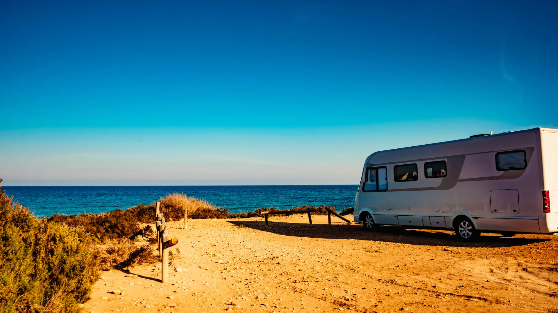 Un camping car garé sur une aire de repos en face à la mer ou l'océan.