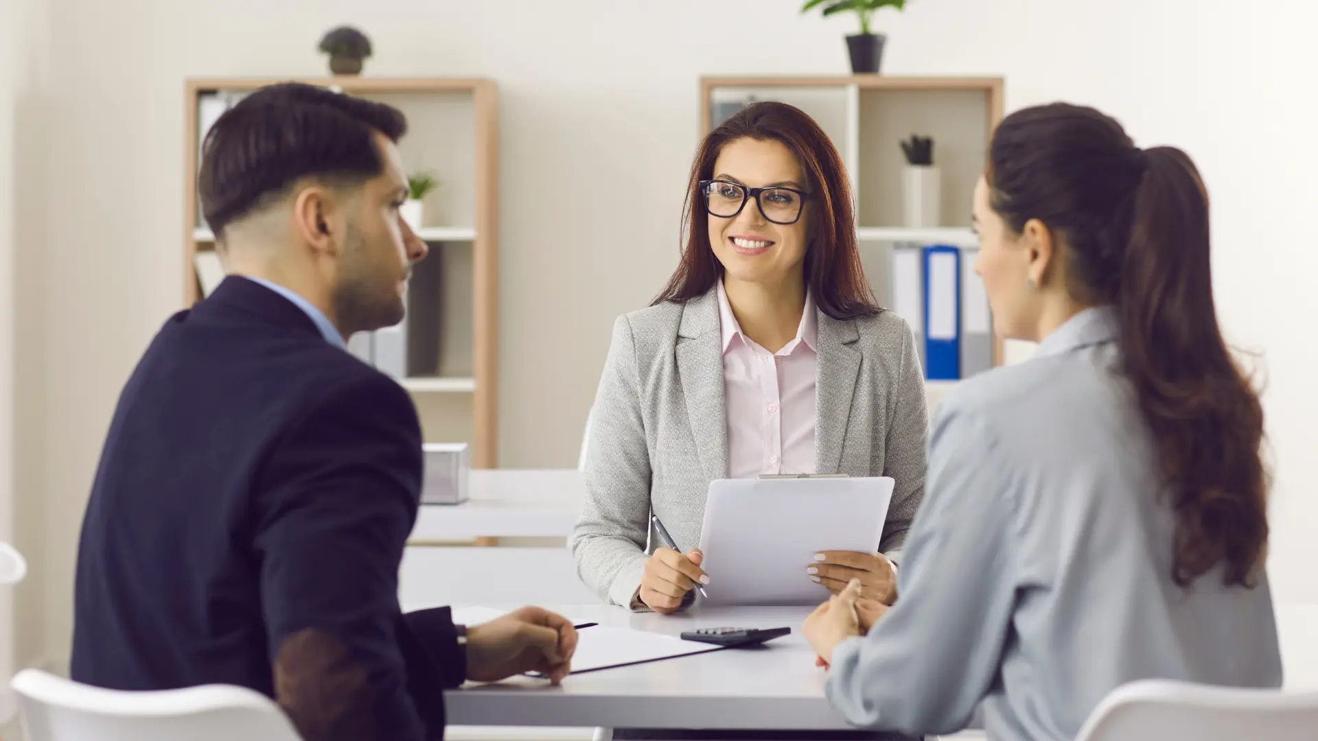 Une courtière en assurance recevant un couple dans son bureau pour un contrat d'assurance.