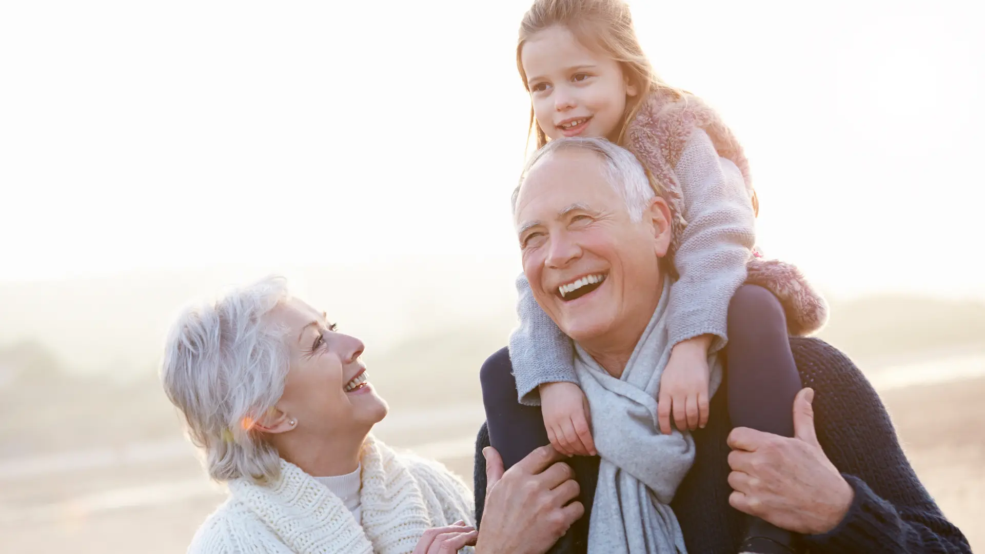 Des grands parents avec leur petite fille, le grand père porte sa petite fille sur le dos.